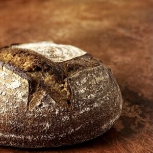 Close-up of a dark whole wheat sourdough bread on a copper-colored backdrop.