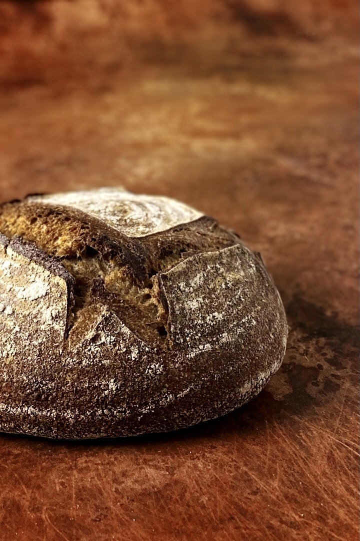 Close-up of a dark whole wheat sourdough bread on a copper-colored backdrop.