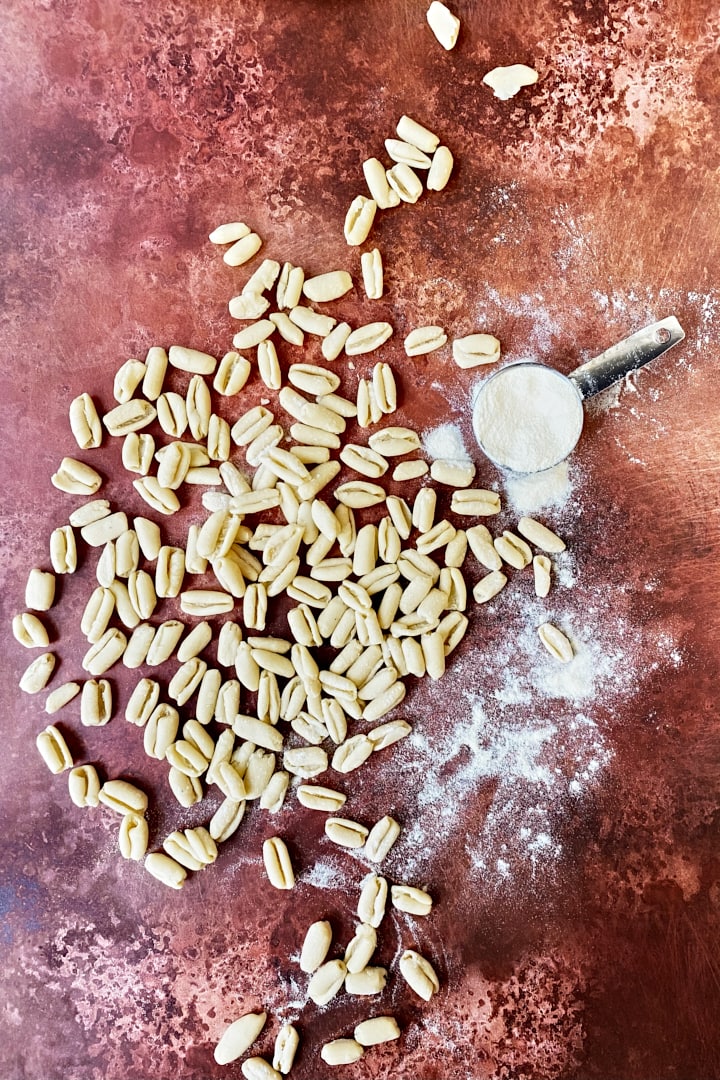 Flatlay of homemade cavatelli pasta and a cup of flour.