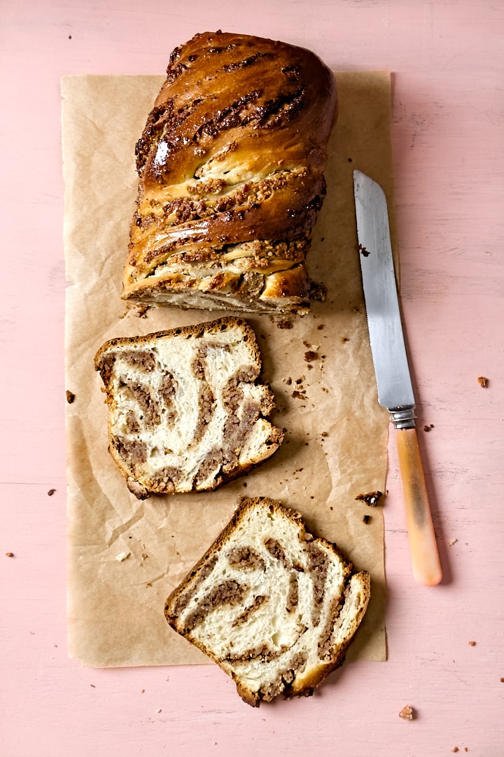 Flatlay of a sourdough babka with two slices cut off to reveal the swirled hazelnut filling.