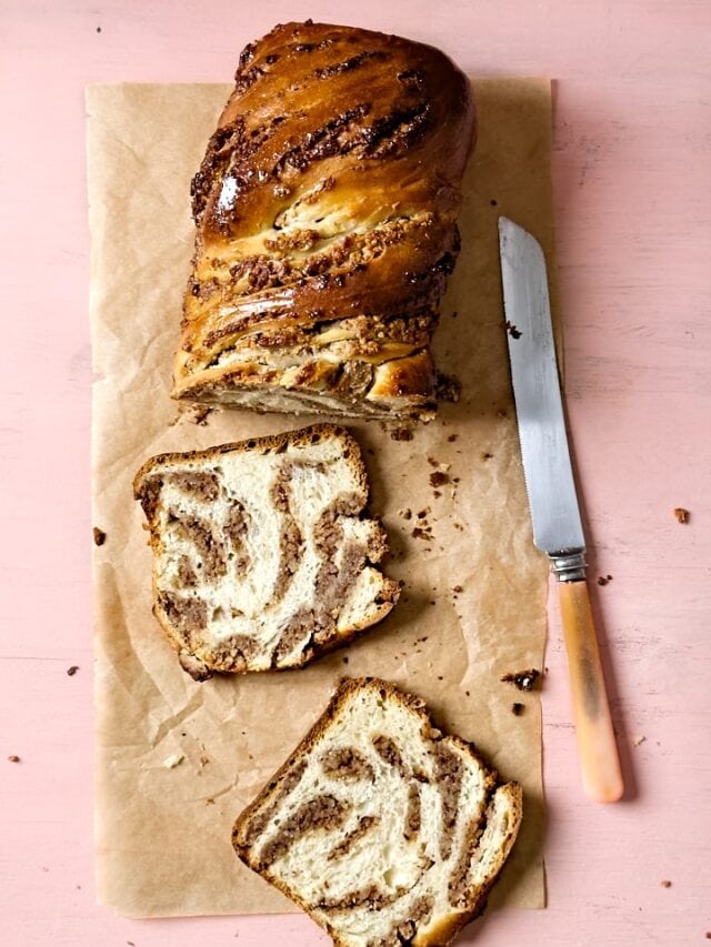 Flatlay of a sourdough babka with two slices cut off to reveal the swirled hazelnut filling.
