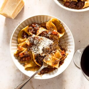 A bowl of pappardelle pasta with slow cooked lamb ragu and parmesan cheese.