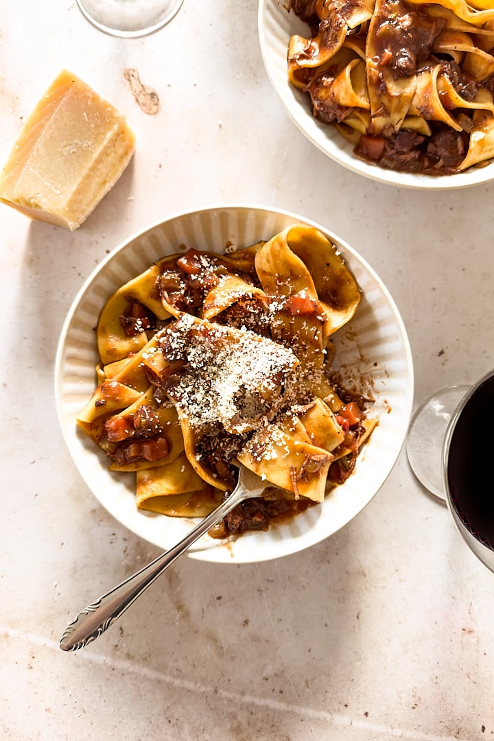 A bowl of pappardelle pasta with slow cooked lamb ragu and parmesan cheese.