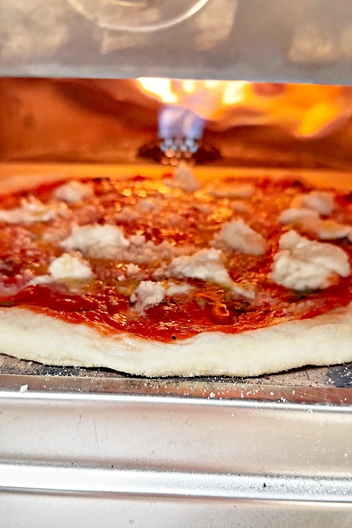 A sourdough pizza being baked in a pizza oven.