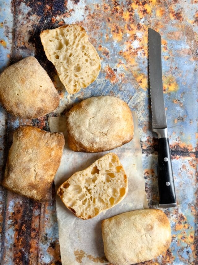 Sourdough ciabatta rolls with a bread knife next to them.