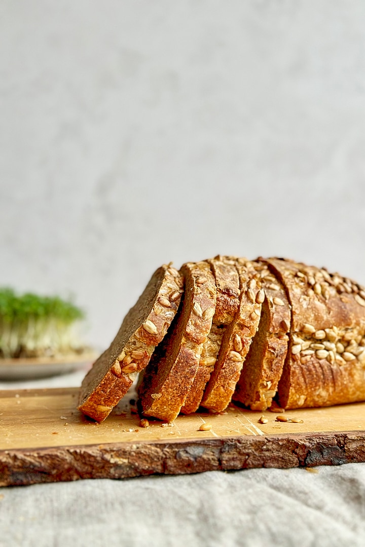 Freshly baked and sliced dark rye sourdough bread on a wooden board.