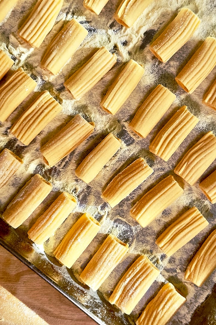Fresh-handrolled rigatoni on a baking tray dusted with semolina flour.