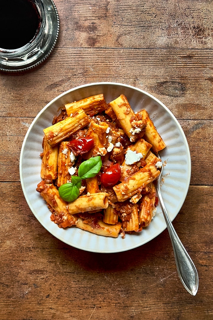 Rigatoni with aubergine ragu on a rustic wooden table.