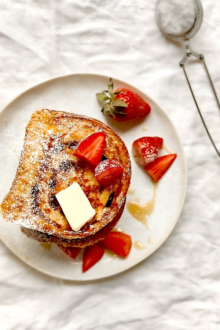 Cinnamon swirl french toast with fresh strawberries on a white plate.