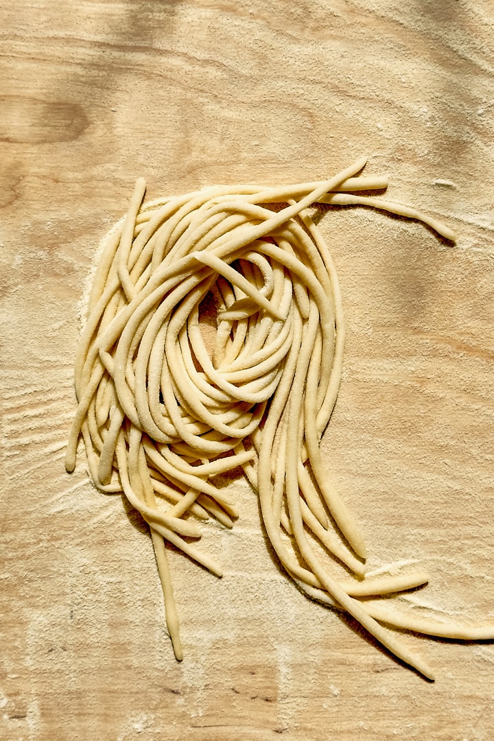 One nest of homemade pici pasta on a wooden board.