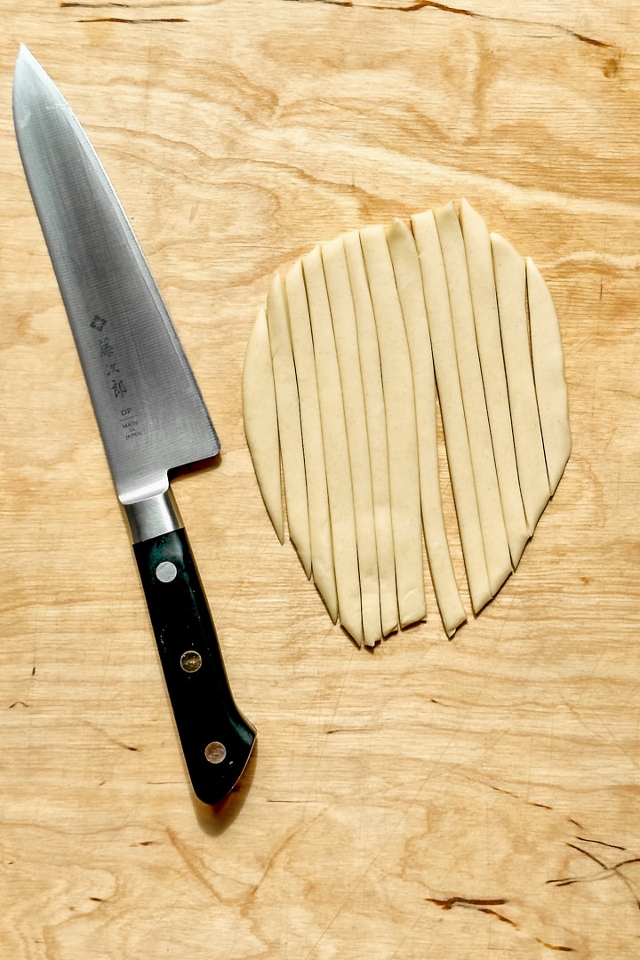 Cutting the dough to make pici pasta into thin strips to roll them out into long pasta strands.