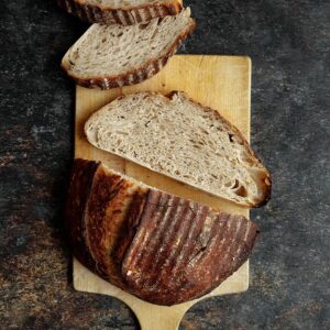 A loaf of rustic sourdough bread on a dark backdrop.