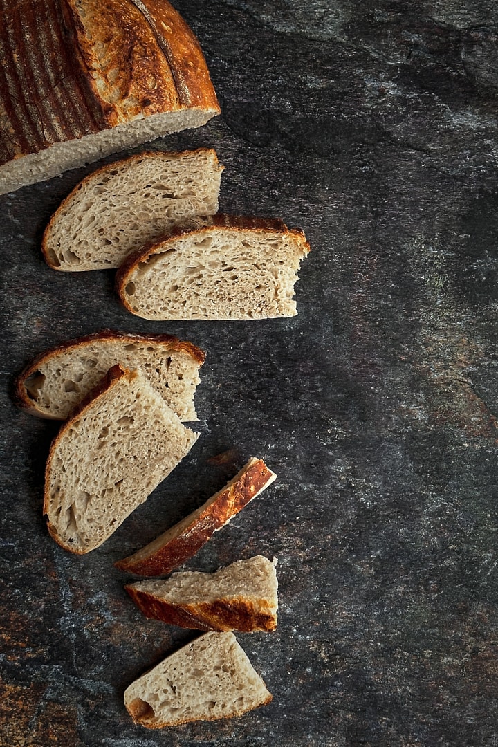 Freshly baked and sliced sourdough bread on a dark stone backdrop.