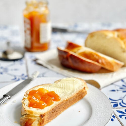 A slice of soft and sweet sourdough bread with butter and apricot jam.