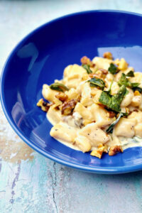 creamy gnocchi with walnuts and sage served on a dark blue pasta plate.
