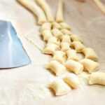 homemade ricotta gnocchi on a wooden pasta board.