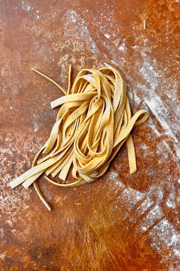 A pasta nest of homemade tagliatalle on a copper backdrop.