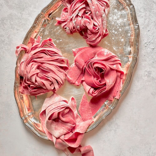 Fresh pink beet pasta on a silver serving tray.