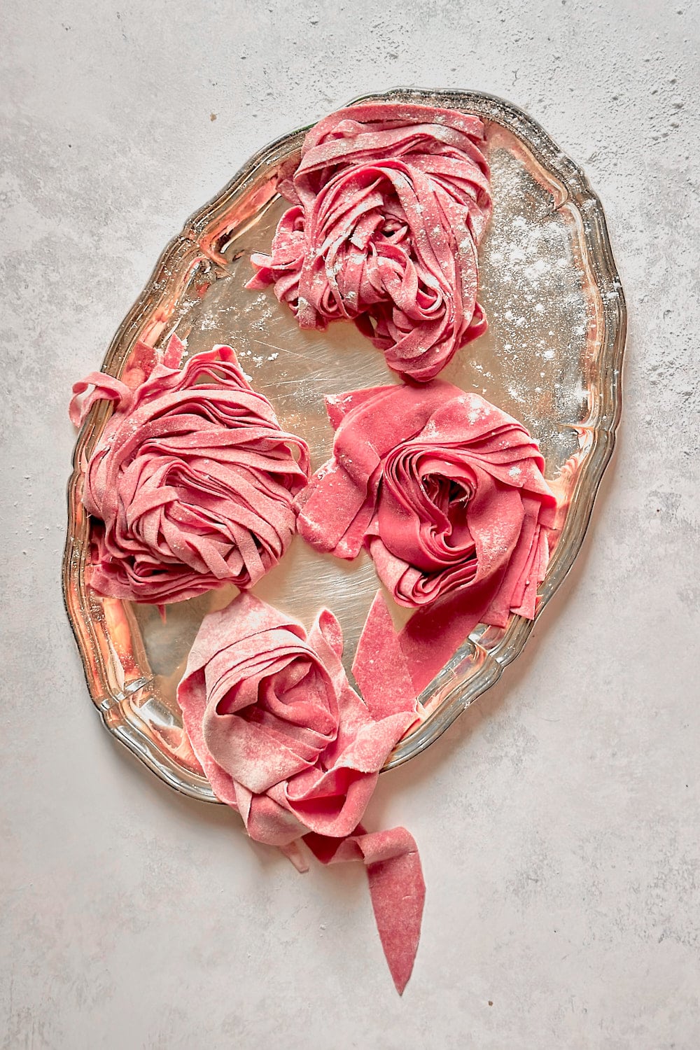 Fresh pink beet pasta on a silver serving tray.