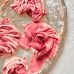 Fresh pink pasta nests made with homemade beet pasta dough.