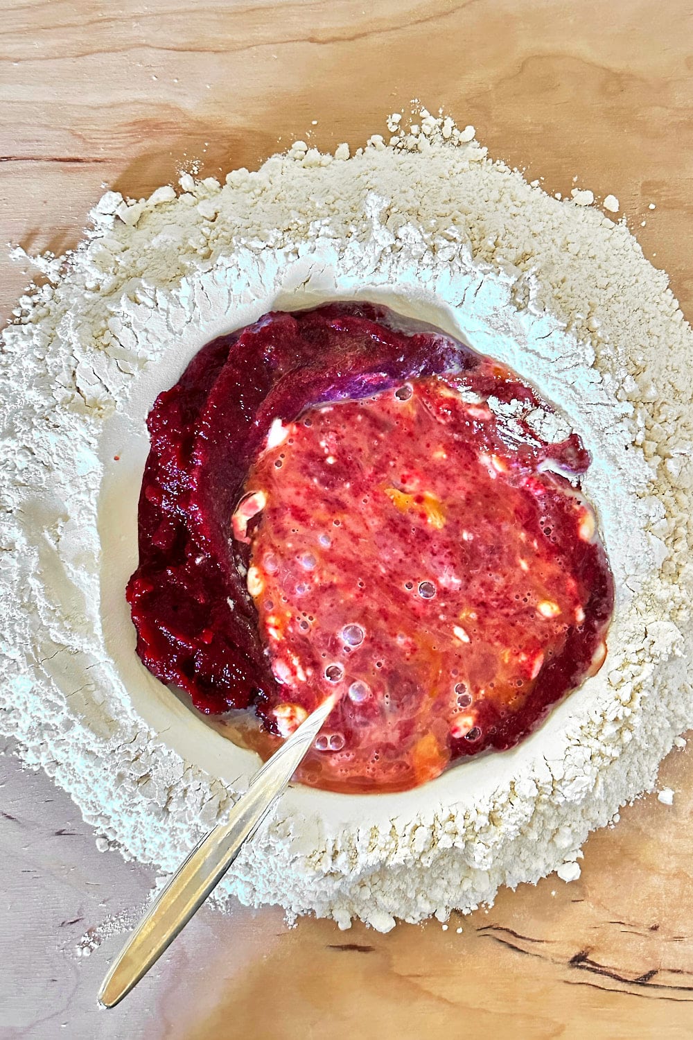 Using a fork to scramble the eggs in the center of the flour well and combine them with the beet puree.