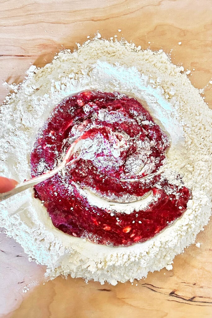 Using a fork to combine the beet-egg mixture with the flour.