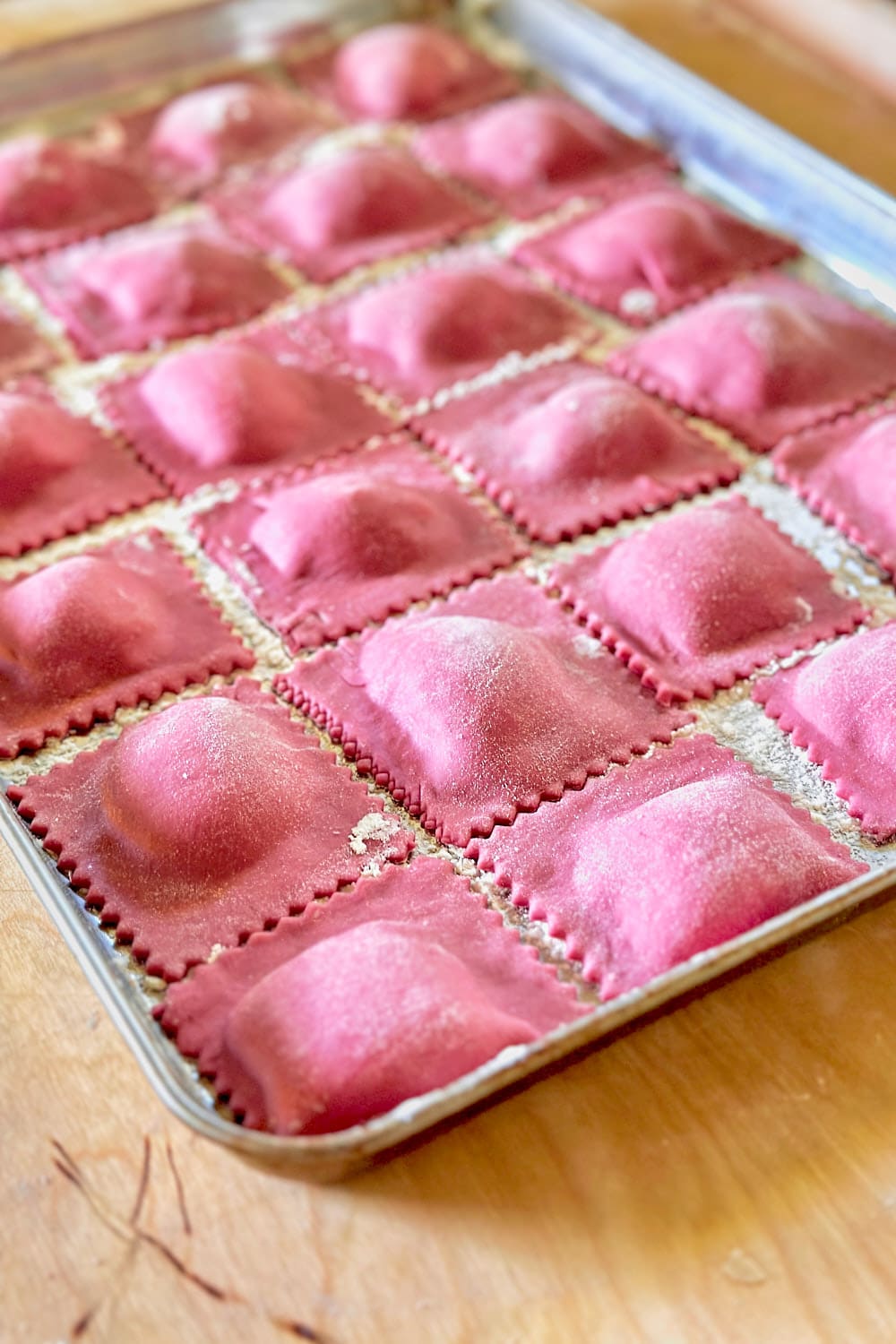Homemade pink beet ravioli on a baking tray.