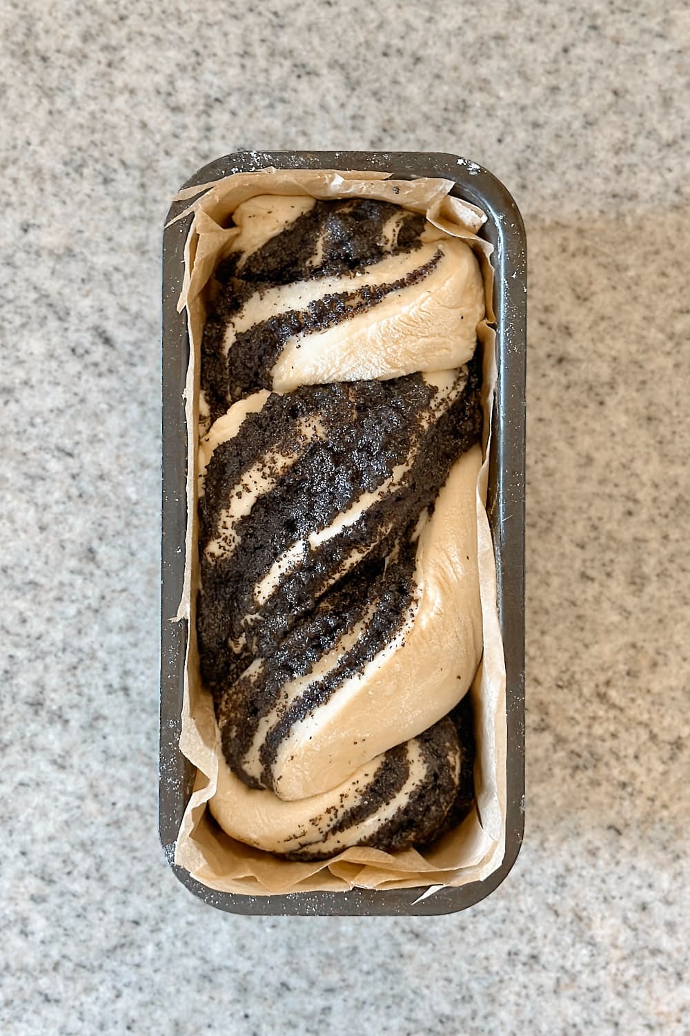 Placing the shaped babka in a loaf pan lined with parchment paper.
